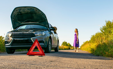 Wall Mural - Beautiful young girl, in despair, she can not continue her journey because of the fact that her car broke down.