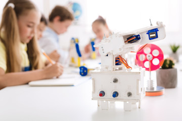 Wall Mural - Robot at desk with schoolchildren at background