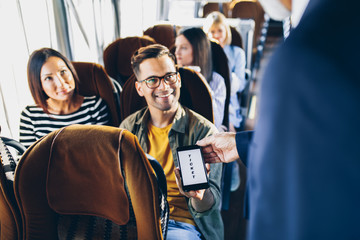 Wall Mural - Young male traveler showing  e-ticket on mobile phone screen to a bus driver.