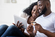 © Prostock-studio - Afro couple purchasing goods in internet with digital tablet