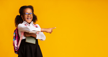 African American Schoolgirl Pointing Finger At Free Space, Studio Shot