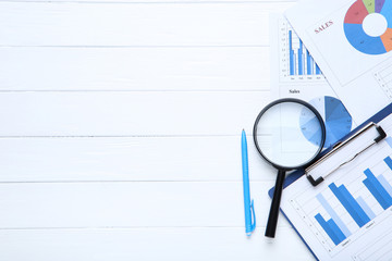 Poster - Financial papers with pen and magnifying glass on wooden table