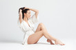 Beautiful young woman woman in white bathrobe on white background