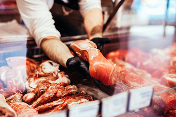 Close up on butcher's hands in gloves working in butchery.