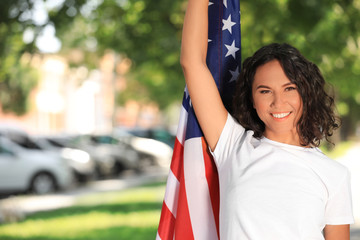 Wall Mural - Happy young woman with American flag on sunny day