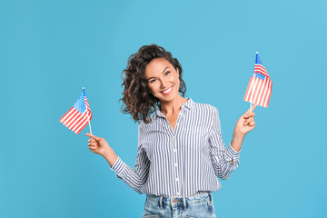 Wall Mural - happy young woman with American flags on blue background