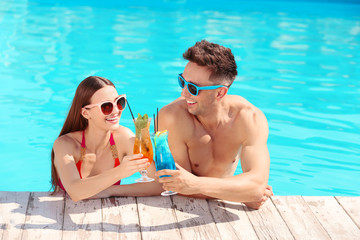 Canvas Print - Happy young couple with cocktails in swimming pool