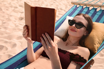 Poster - Young woman reading book in hammock on beach