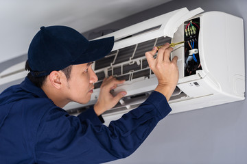 Wall Mural - Electrician with screwdriver repairing air conditioner indoors