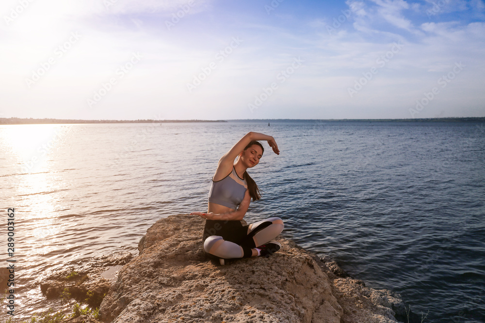 Young woman practicing yoga near river