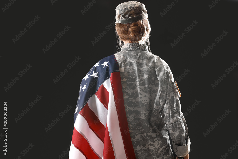 Young female soldier with USA flag on dark background, back view