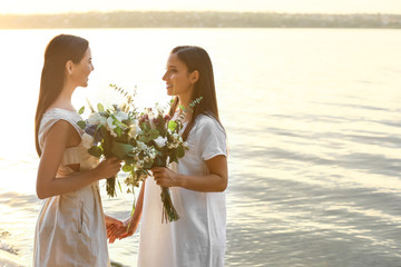 Wall Mural - Beautiful lesbian couple on their wedding day near river