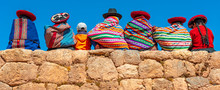 Panoramic Photograph Of Quechua Indigenous Women In Traditional Clothing With A Boy Sitting On An Ancient Inca Wall In Chinchero, Cusco Province, Peru.