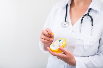 Wall Mural - Woman doctor holding yellow pill box with daily medication