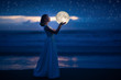 © Anton - A young girl on a night beach holds the moon, with a starry sky. Art photography