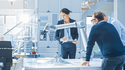 Aufkleber - Diverse Team of Industrial Robotics Engineers Gathered Around Table With Robot Arm, They Manipulate and Program it to Pick Up and Move Metal Component. Bright Facility, Creative People