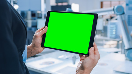 Aufkleber - Engineer Holds Green Mock-up Screen Digital Tablet Computer. In the Background Team of Industrial Engineers Working with Functional Robot Arm in Modern Bright Research Facility