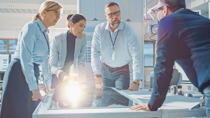 Wall Mural - Team Meeting of Renewable Energy Engineers Working on an Innovative More Efficient Solar Panel Battery Concept. Group of Specialists Gathered Around Table, Solving Problems. Bright Research Facility