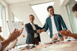 © Friends Stock - New team member. Two cheerful colleagues shaking hands and smiling while having a meeting in the modern office