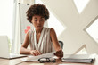 © Friends Stock - Young expert. Beautiful afro american woman analyzing documents while sitting in modern office