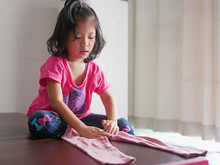 Little Asian Baby Girl Learning To Fold Her Own Pants - Children Help Doing Household Chores