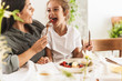 Image of caucasian family mother and little daughter eating tasty food together while having breakfast at home in morning
