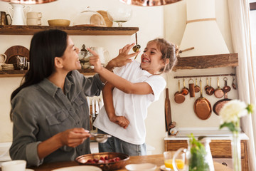 Wall Mural - image of cheerful family woman and her little daughter cooking together meal with raspberry at cozy 