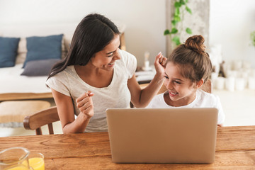 Wall Mural - image of cheerful family woman and her little daughter smiling and using laptop computer together in