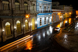 Fototapeta Londyn - Night on a Cuban street after the rain with lights and moving cars