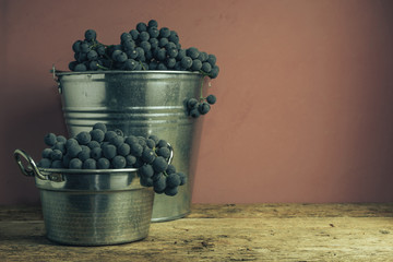 Poster - Beautiful wine grapes of silver basket on a old oak wooden table and red wall background.