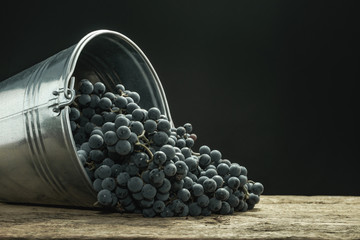 Poster - Beautiful wine grapes of silver basket on a old oak wooden table and black background.