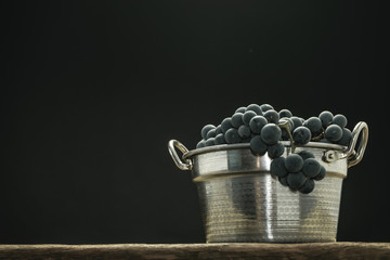 Poster - Beautiful wine grapes of silver basket on a old oak wooden table and black background.