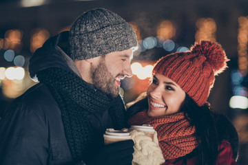 photo of two overjoyed people with hot tea beverage in hands spending x-mas evening at decorated par