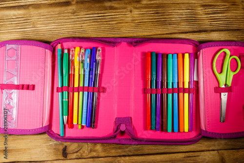 Fotografía Pencil case containing pens, pencils, felt-tip pens, scissors and ruler on wooden desk