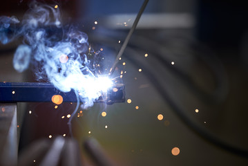 The connection of two parts by welding close-up. Welding work. Sparks fly in different directions.