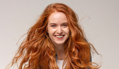  Beautiful redhead girl laughing, looking at camera on light background
