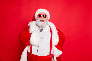 Close up photo of cheerful funny fat pop star santa claus with big belly in headwear hat sing songs wear stylish style trendy eyeglasses eyewear isolated over red background