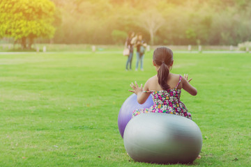 Wall Mural - Happiness girl in the floral skirt relax and play with a big ball on green field in the public garden.