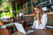 © Dragana Gordic - Image of woman using laptop while sitting at her desk. Young businesswoman sitting in the coffee shop and working on laptop. Digital displays surrounding us from everywhere