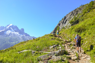 hikers with hiking poles in french alps near chamonix on a trail to lac blanc with mont blanc view. 