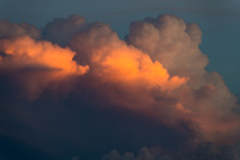 Cloudscape Of Fluffy Storm Clouds Illuminated In Hues Of Yellow, Orange, Pink, And Purple By The Light Of Sunset