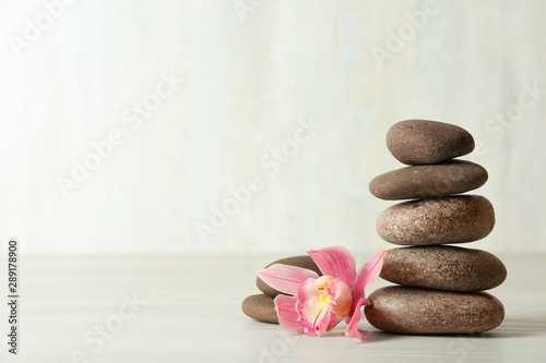 Stack of spa stones and flower on table against white background, space for text Wallpaper Mural