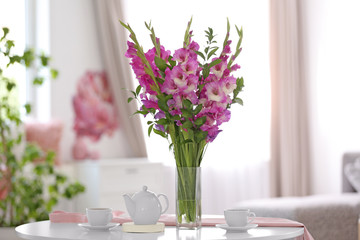 Canvas Print - Vase with beautiful pink gladiolus flowers on wooden table in living room