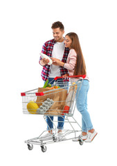 Canvas Print - Young couple with full shopping cart on white background