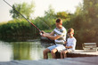 © New Africa - Dad and son fishing together on sunny day