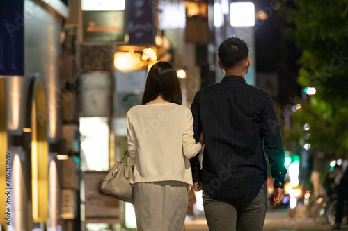 夜の繁華街で手を繋いで歩く男女の後ろ姿 Stock 写真 Adobe Stock