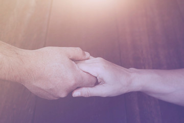 Wall Mural - close up of man  and woman are holding hands and prays together on wooden table, Christian background with copy space, helping hands concept