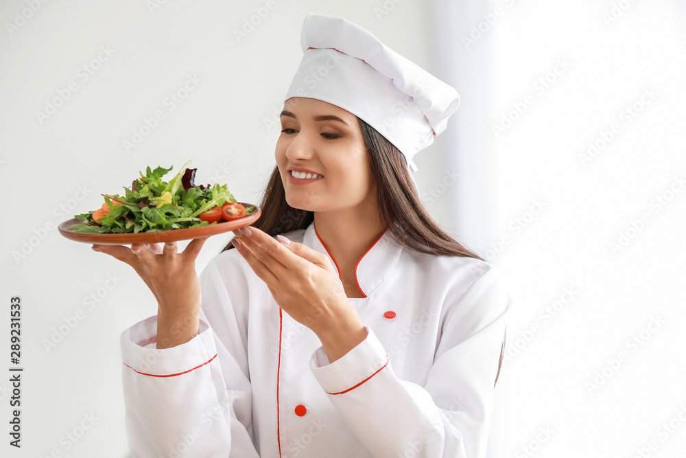 Beautiful female chef with salad in kitchen