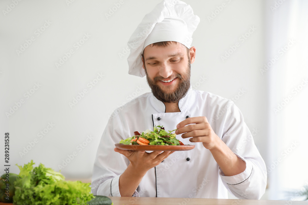 Handsome male chef with salad in kitchen