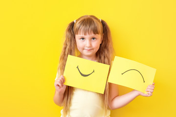 Poster - Little girl with drawn smiling and upset mouths on sheets of paper against color background